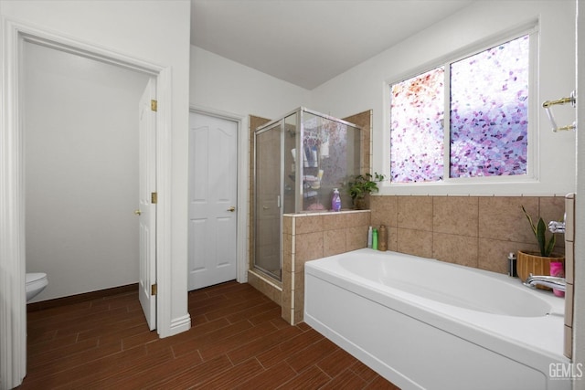bathroom with wood tiled floor, a shower stall, toilet, and a bath