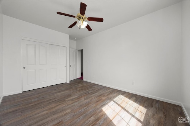 unfurnished bedroom with baseboards, ceiling fan, a closet, and dark wood-type flooring