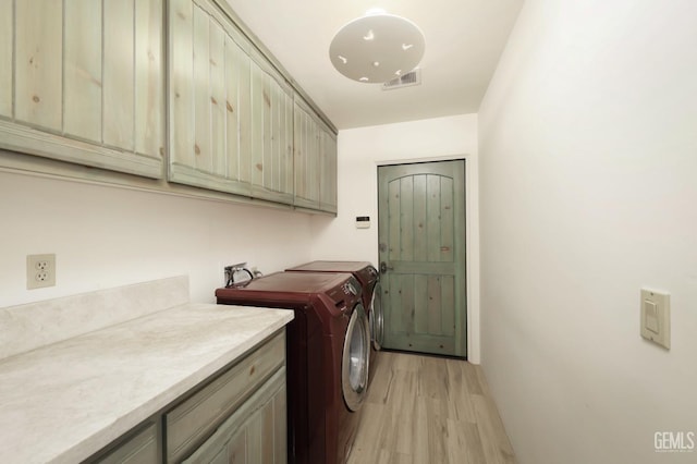 washroom featuring cabinet space, visible vents, light wood-style floors, and independent washer and dryer