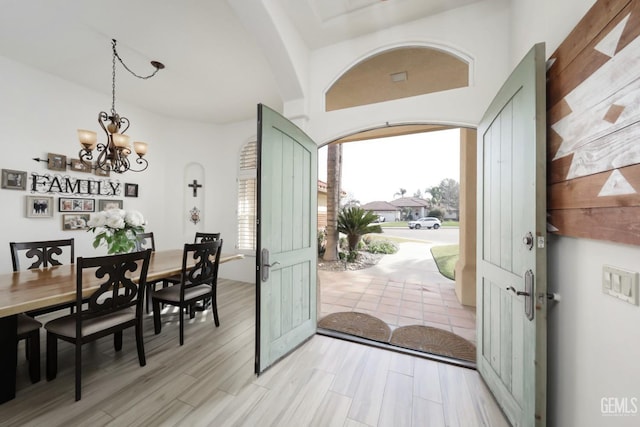 foyer entrance featuring light wood-style floors, arched walkways, and a chandelier