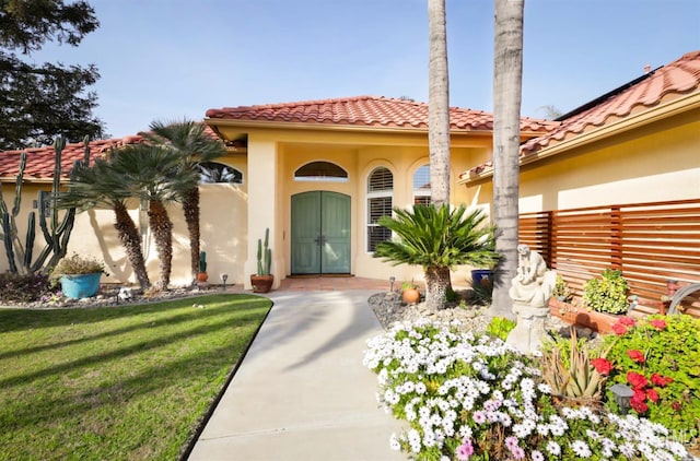 doorway to property with a yard, a tile roof, and stucco siding