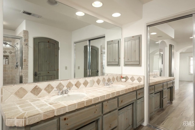 full bathroom featuring double vanity, wood finished floors, a sink, and visible vents