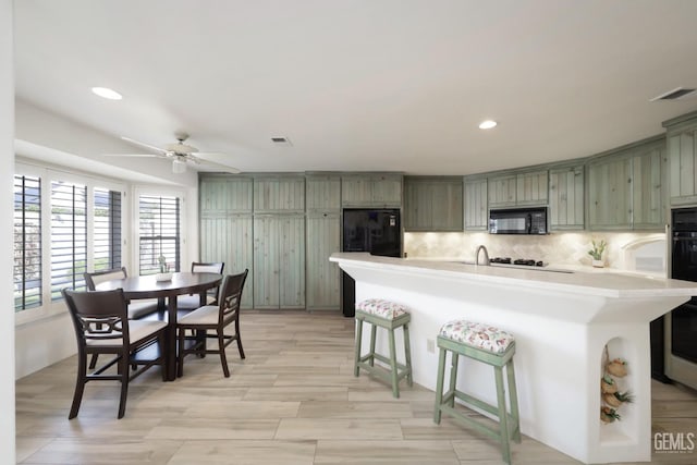 kitchen featuring black appliances, visible vents, light countertops, and decorative backsplash