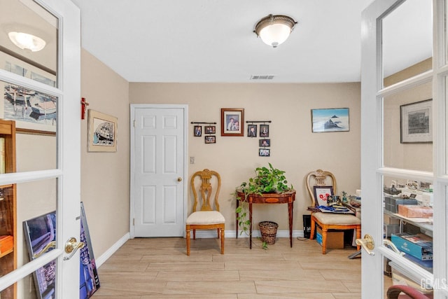 sitting room featuring baseboards, visible vents, and light wood-style floors