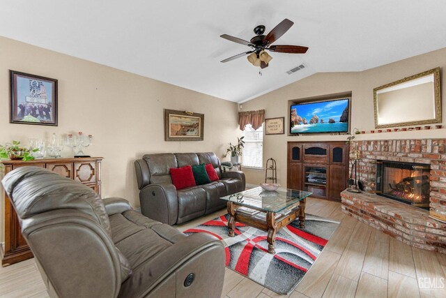living room with visible vents, a fireplace, a ceiling fan, light wood-style flooring, and vaulted ceiling