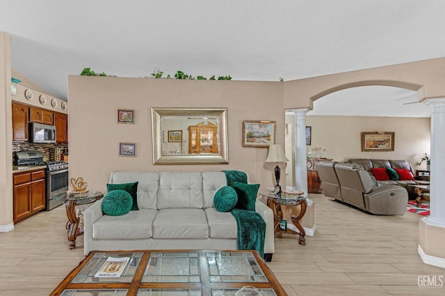 living room with ornate columns, arched walkways, baseboards, and light wood-type flooring