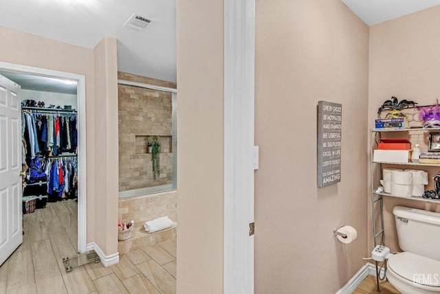 bathroom with visible vents, a stall shower, toilet, and a spacious closet