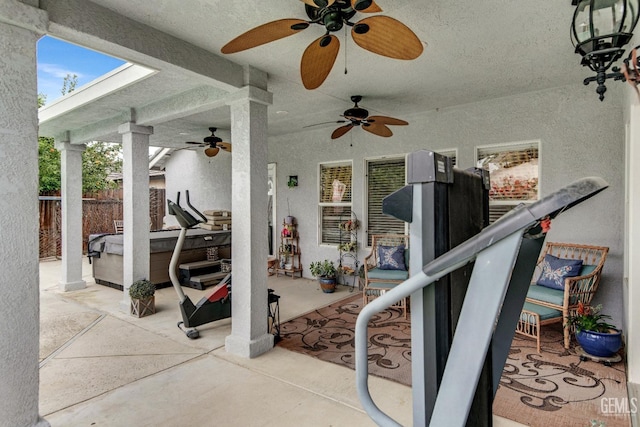 view of patio / terrace featuring ceiling fan, a hot tub, and fence