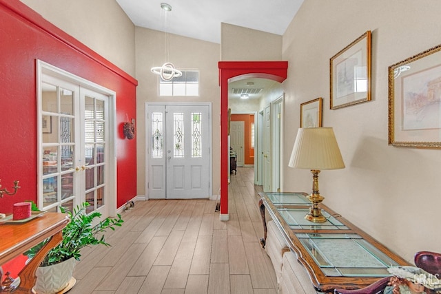 foyer entrance with high vaulted ceiling, a chandelier, baseboards, and light wood finished floors