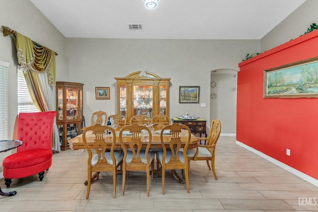 dining space with visible vents, arched walkways, baseboards, and wood finished floors