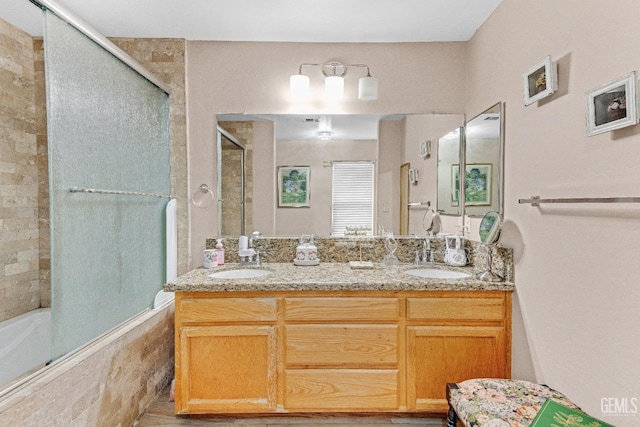 full bathroom featuring double vanity, tiled shower / bath, and a sink