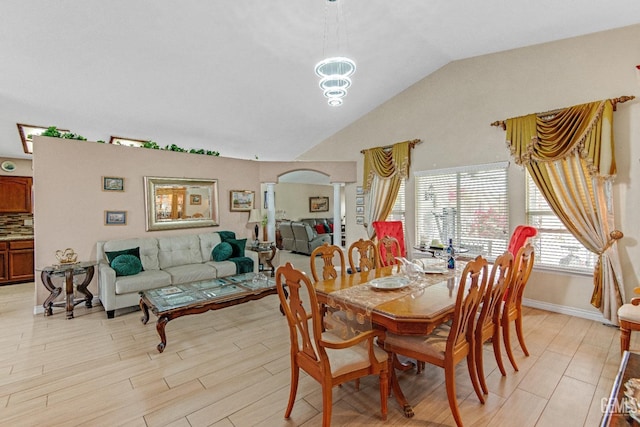 dining area featuring baseboards, light wood finished floors, ornate columns, and lofted ceiling