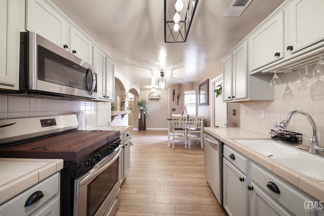 kitchen featuring appliances with stainless steel finishes, white cabinets, and pendant lighting