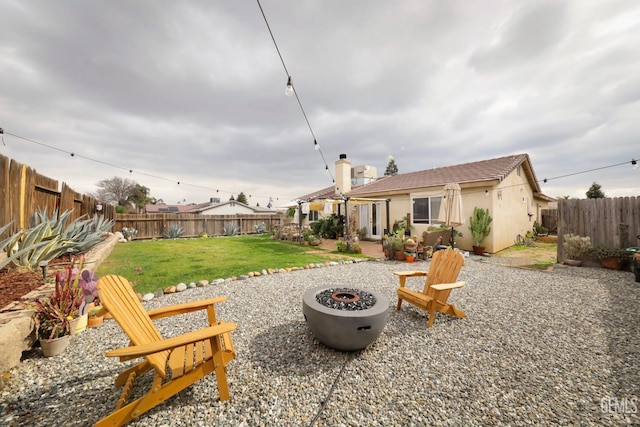 back of property featuring a yard, a patio, and a fire pit