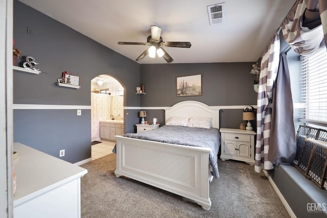 carpeted bedroom featuring lofted ceiling, ceiling fan, and ensuite bath