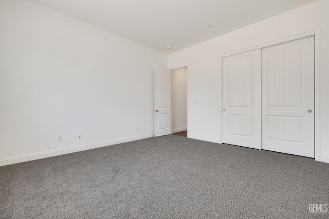 unfurnished bedroom featuring a closet and dark colored carpet