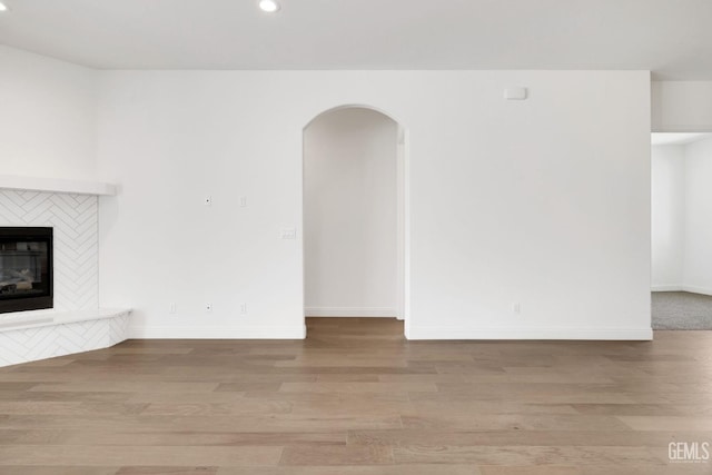 unfurnished living room with a tile fireplace and light hardwood / wood-style flooring