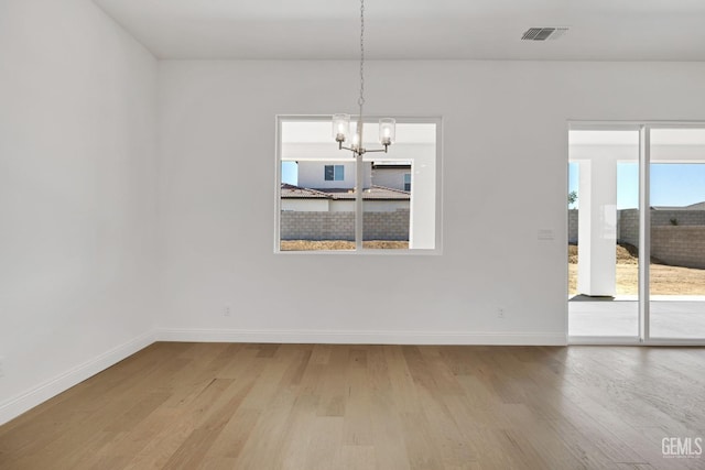 unfurnished dining area with a notable chandelier and light hardwood / wood-style flooring