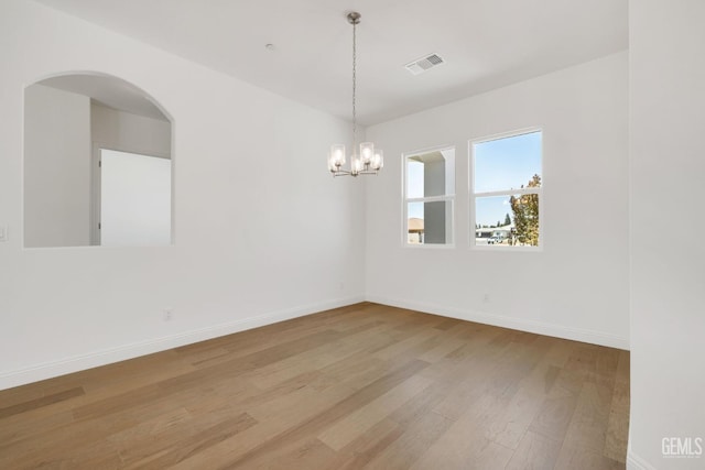 spare room with an inviting chandelier and light hardwood / wood-style flooring