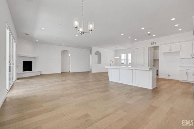 unfurnished living room with an inviting chandelier and light hardwood / wood-style floors