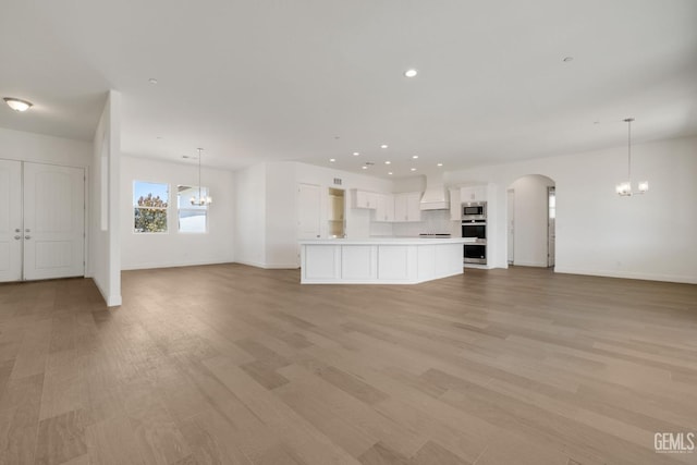 unfurnished living room with light hardwood / wood-style floors and a notable chandelier