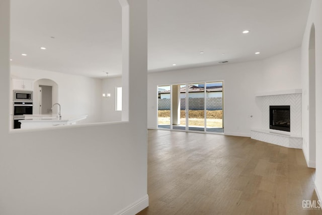 unfurnished living room with hardwood / wood-style floors, a fireplace, and sink