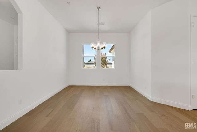 unfurnished dining area with a notable chandelier and light wood-type flooring