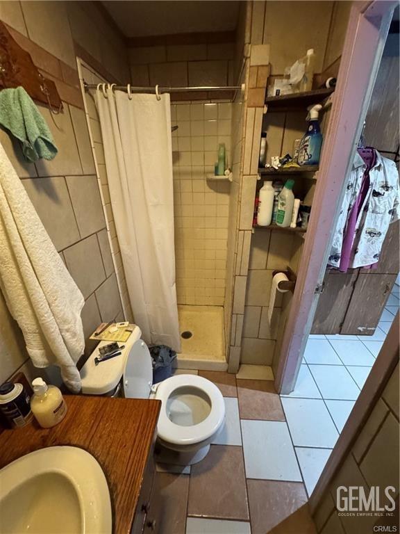 bathroom featuring a sink, tile patterned flooring, a stall shower, and toilet