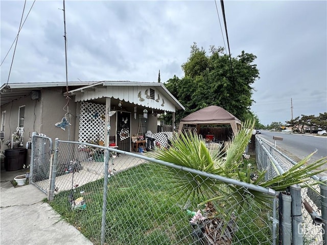 bungalow-style house with fence private yard, stucco siding, and a gazebo