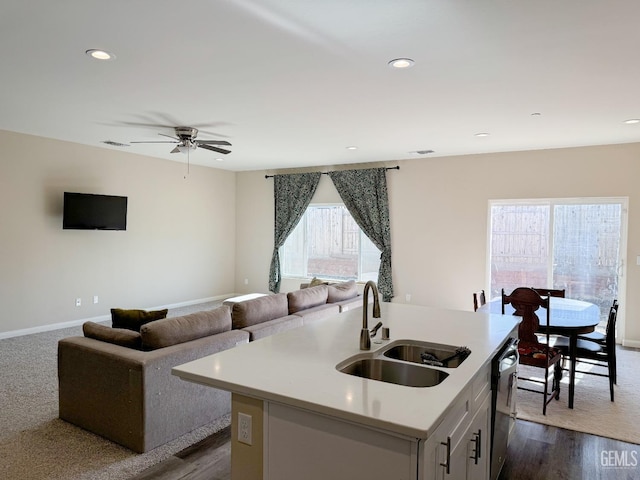 kitchen with a kitchen island with sink, sink, stainless steel dishwasher, ceiling fan, and dark hardwood / wood-style floors