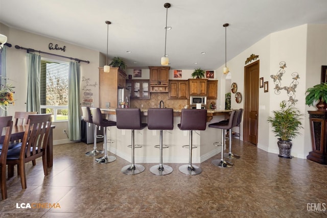 kitchen with decorative backsplash, a kitchen breakfast bar, decorative light fixtures, and appliances with stainless steel finishes