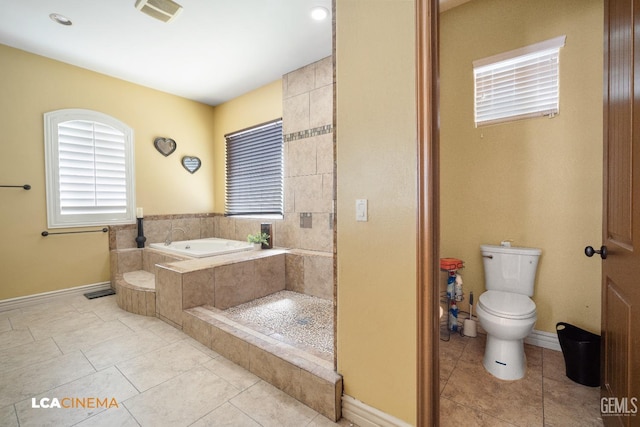 bathroom with toilet, tile patterned floors, and tiled tub