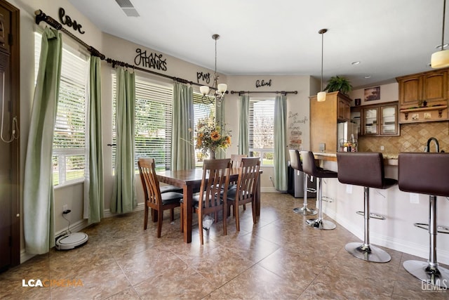 dining area with a notable chandelier, light tile patterned floors, and a wealth of natural light