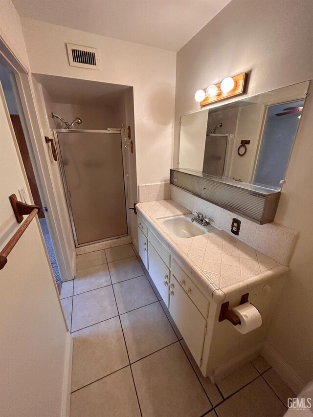 bathroom with tile patterned flooring, vanity, and a shower with shower door