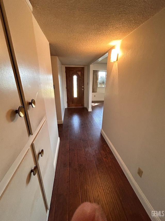 doorway to outside featuring dark wood-type flooring and a textured ceiling