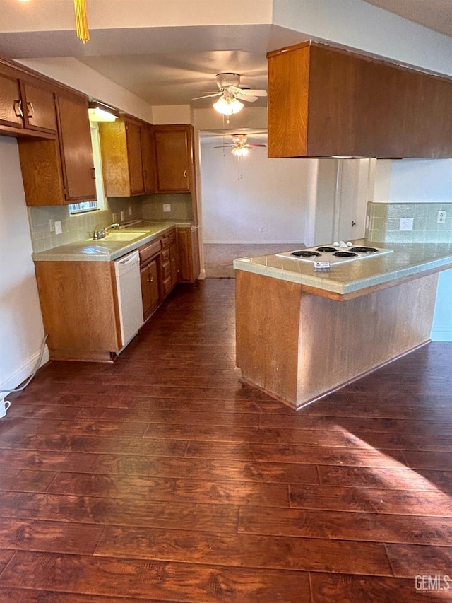 kitchen featuring dishwasher, dark wood-type flooring, ceiling fan, decorative backsplash, and kitchen peninsula