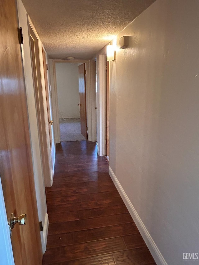 hallway featuring a textured ceiling and dark hardwood / wood-style floors