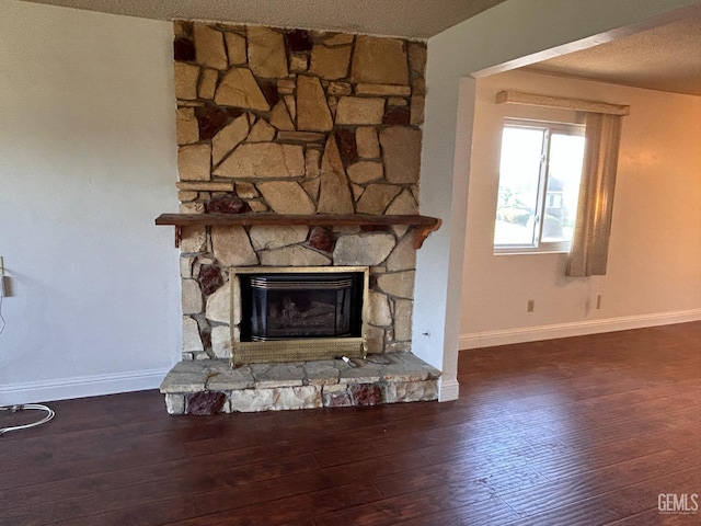 details featuring hardwood / wood-style floors, a stone fireplace, and a textured ceiling