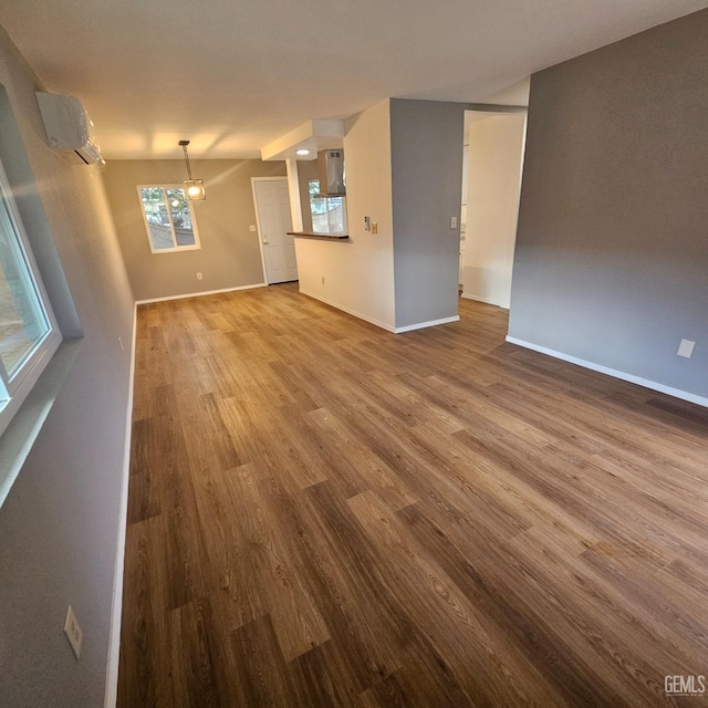 unfurnished living room featuring a wall mounted AC and hardwood / wood-style floors