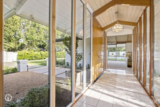 doorway with light tile patterned flooring and lofted ceiling