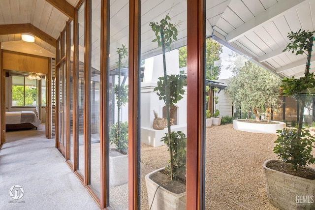 doorway featuring vaulted ceiling with beams, plenty of natural light, and light colored carpet