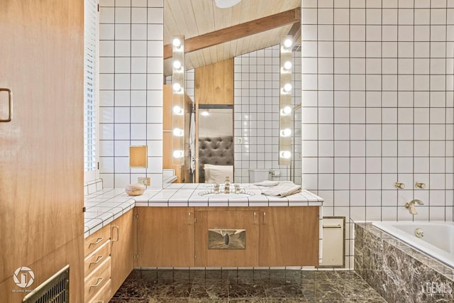 bathroom featuring tiled bath, vanity, lofted ceiling with beams, and tile walls