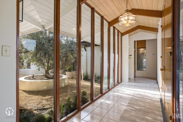 unfurnished sunroom featuring vaulted ceiling with beams and plenty of natural light