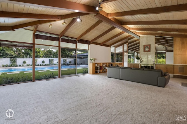 unfurnished living room featuring carpet flooring, wooden walls, beam ceiling, high vaulted ceiling, and wooden ceiling