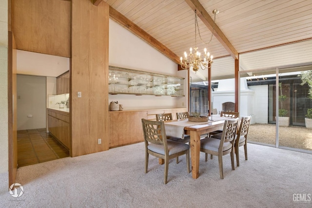 carpeted dining space with beam ceiling, high vaulted ceiling, a notable chandelier, and wood walls