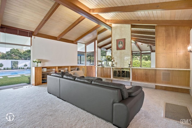 living room featuring beamed ceiling, high vaulted ceiling, carpet floors, and wooden walls