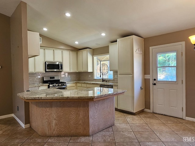 kitchen featuring stainless steel appliances, sink, vaulted ceiling, light stone counters, and kitchen peninsula