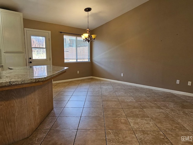 unfurnished dining area with a notable chandelier and light tile patterned flooring