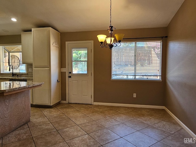 unfurnished dining area with an inviting chandelier, light tile patterned floors, and sink