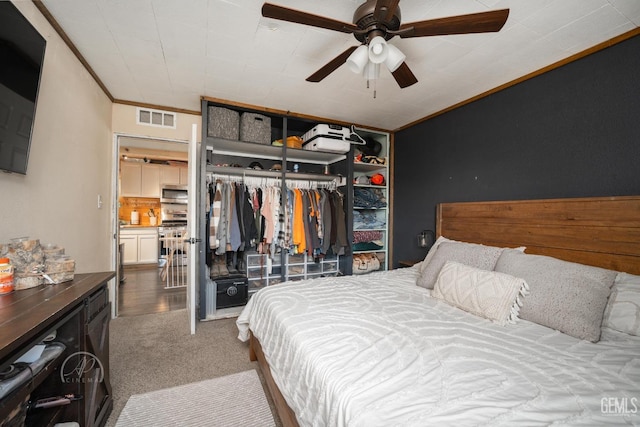 bedroom featuring ceiling fan, ornamental molding, carpet floors, and a closet